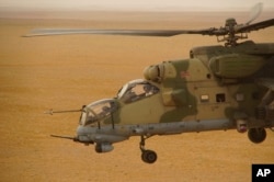 FILE - A Russian military helicopter flies over a desert in Deir el-Zour province, Syria, Sept. 15, 2017.