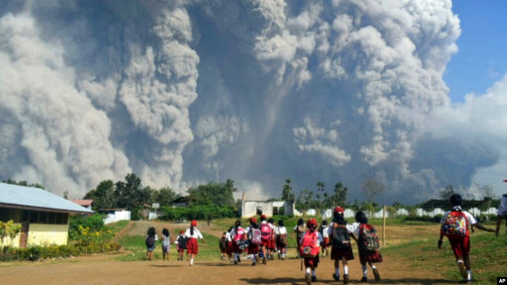 Niños de una escuela observan la erupción del monte Sinabung en Sumatra del Norte, Indonesia, el lunes, 19 de febrero de 2018.