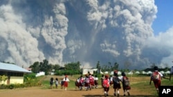 Niños de una escuela observan la erupción del monte Sinabung en Sumatra del Norte, Indonesia, el lunes, 19 de febrero de 2018.