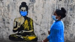 A resident wearing a facemask amid concerns over the spread of the COVID-19 novel coronavirus walks past a graffiti of Buddha wearing facemask, in Mumbai on March 16, 2020.