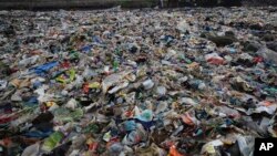 2018年6月4日，一名男子在印度孟买堆满塑料和其它垃圾的阿拉伯海岸上行走。