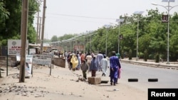 Quelques personnes marchent sur cette avenue après avoir fui une attaque de Boko Haram à Maiduguri dans l'Etat de Borno, Nigeria, 14 mai 2015. 