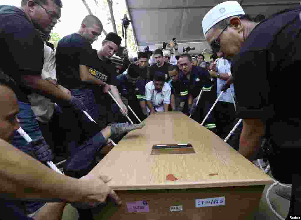 The coffin of twenty-nine-year-old Malaysia Airlines MH17 First Officer Ahmad Hakimi Hanapi is lowered during his burial in Putrajaya, Aug. 22, 2014.