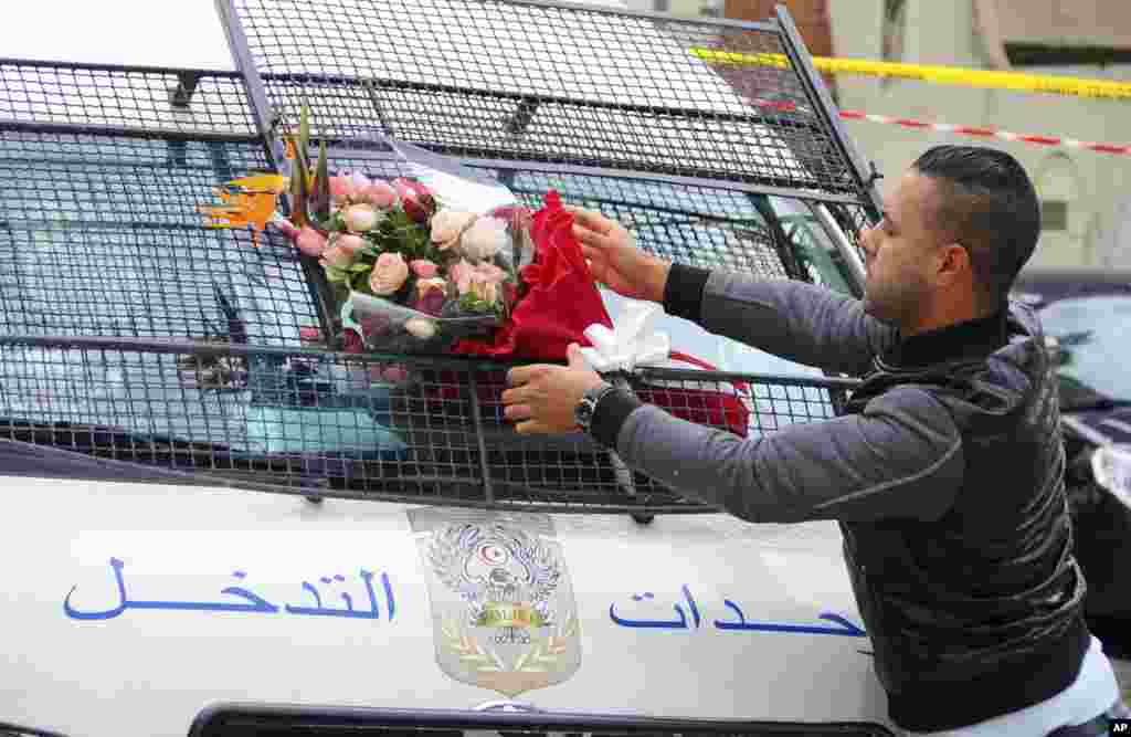 Một người đàn ông đặt một bó hoa lên một chiếc xe cảnh sát, gần chiếc xe buýt phát nổ ở Tunis, Tunisia. Bộ Nội vụ Tunisia cho biết 10 kilogram chất nổ quân sự đã được sử dụng trong một cuộc tấn công nhắm vào chiếc xe buýt chở nhân viên an ninh của tổng thống. Ít nhất 12 người thiệt mạng trong vụ tấn công