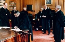 Associate Justice David Souter signs documents of office at the Supreme Court after being sworn in as the newest member of the high court in Washington, Oct. 9, 1990.