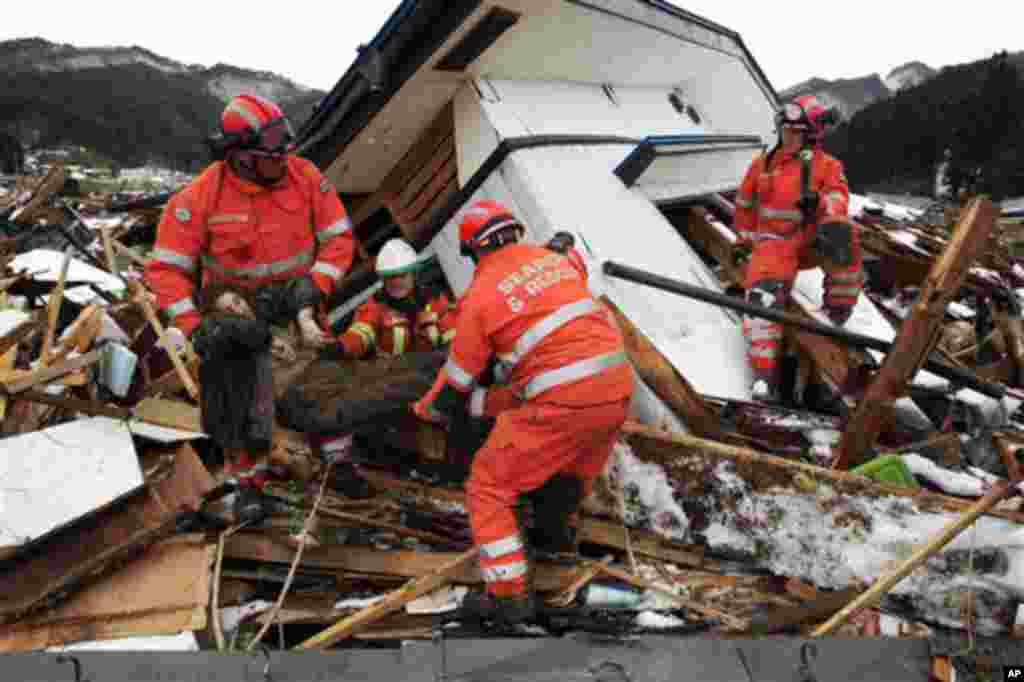 Members of a British search and rescue team recover the body of an unidentified woman from a destroyed house as they search for survivors in Kamaishi. (AP Image)