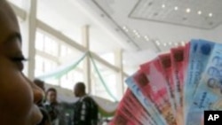 FILE: A woman holds Ghana's currency. Taken April 4, 2012