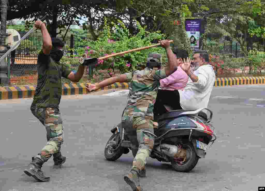 Members of the Karnataka Reserve Police Force swing their sticks to beat two men on a scooter who rode too close to a barricade set up on a street in Mangalore amid heightened security due to protests over India’s new citizenship law.