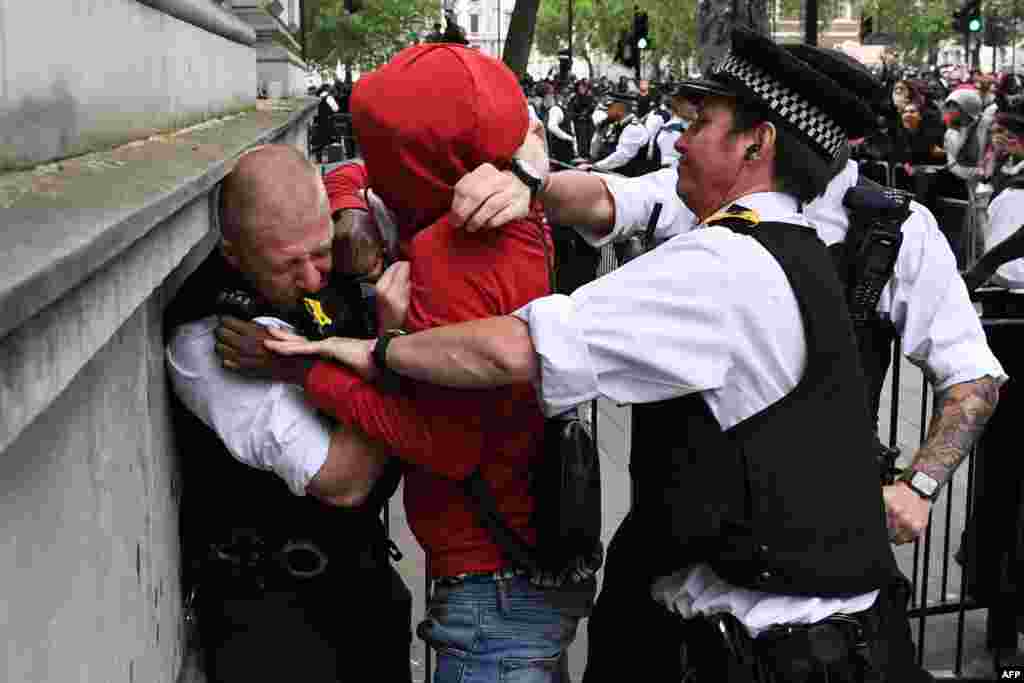 Police officers react as they attempt to detain a protester near the entrance to Downing Street, during an anti-racism demonstration in London.