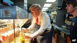 El candidato presidencial republicano, el expresidente Donald Trump, sirve papas fritas mientras un empleado observa durante una visita a McDonald's en Feasterville-Trevose, Pensilvania, el 20 de octubre de 2024.