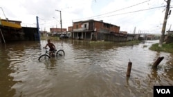 Seorang bocah mendorong sepedanya di jalanan yang digenangi banjir di Sao Paulo, Brazil.
