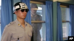 在朝鲜半岛北纬三十八度停战线上的村落板门店非军事区，韩国宪兵在联合国停战村站岗，朝鲜一名士兵在窗后观察。（资料照片）