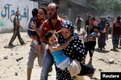 Palestinians run following what police said was an Israeli air strike on a house in Gaza city July 9, 2014. At least 23 people were killed across Gaza, Palestinian officials said.
