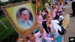 Warga berdoa sambil memegang foto Raja Thailand Bhumibol Adulyadej di Rumah Sakit Siriraj tempat raja dirawat, di Bangkok (12/10). (AP/Sakchai Lalit)