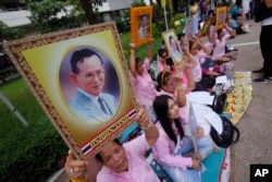 Thais pray while holding up portraits of Thailand's King Bhumibol Adulyadej at Siriraj Hospital where the king is being treated in Bangkok, Thailand, Oct. 12, 2016.