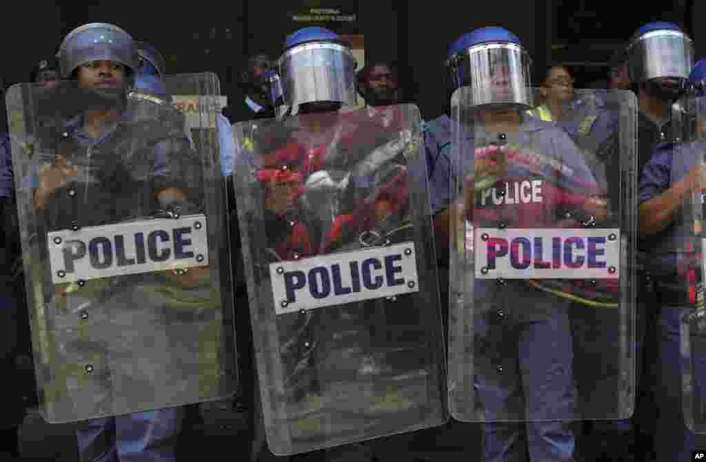 Imagem dos manifestantes refletidas nos escudos da policia de choque.
