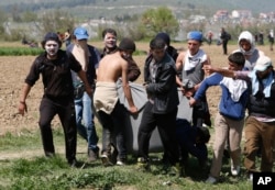 Migrants carry a wounded man in a blanket during a protest at the northern Greek border point of Idomeni, Greece, April 10, 2016.