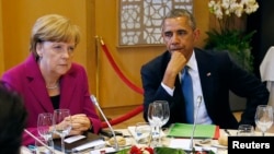 FILE - U.S. President Barack Obama (R) and German Chancellor Angela Merkel listen during the G7 Summit working dinner in Brussels.