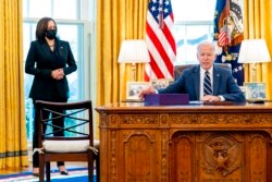 FILE - President Joe Biden, accompanied by Vice President Kamala Harris, looks up after signing the American Rescue Plan, a coronavirus relief package, in the Oval Office of the White House, March 11, 2021.