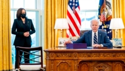 President Joe Biden, accompanied by Vice President Kamala Harris, looks up after signing the American Rescue Plan, a coronavirus relief package, in the Oval Office of the White House, March 11, 2021, in Washington.