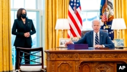President Joe Biden, accompanied by Vice President Kamala Harris, looks up after signing the American Rescue Plan, a coronavirus relief package, in the Oval Office of the White House, March 11, 2021, in Washington.