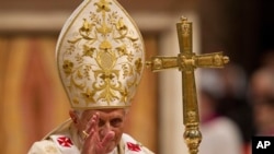 Pope Benedict XVI delivers his blessing as he leaves after celebrating Christmas Mass in St. Peter's Basilica at the Vatican, December 24, 2011.