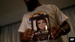 Un miembro del movimiento Free Alex Saab sostiene una imagen de Alex Saab durante una conferencia de prensa en Caracas, Venezuela, el lunes 15 de agosto de 2022.