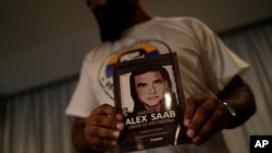 Un miembro del movimiento Free Alex Saab sostiene una imagen de Alex Saab durante una conferencia de prensa en Caracas, Venezuela, el lunes 15 de agosto de 2022.