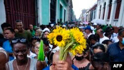 People holding flowers line up to pay they respects to firefighters who died in a huge fire at an oil depot in early August, during the funeral service at the Firemen's Museum in Matanzas, Cuba, Aug. 19, 2022. 