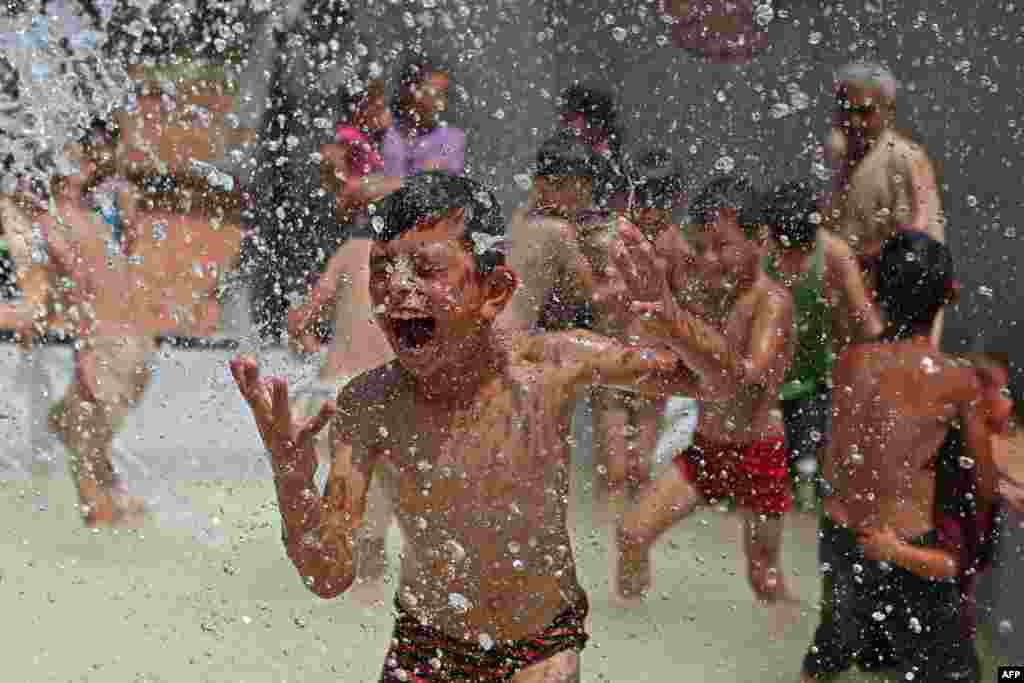 A Syrian boy reacts as he gets sprayed with water in a swimming pool set up by volunteers, at a camp for the displaced in the rebel-held town of Kafr Yahmul in the northern countryside of Idlib.