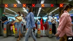 FILE - Commuters walk through a subway station during the morning rush hour in the central business district in Beijing, Aug. 9, 2022.