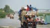 Satu keluarga mengungsi sambil membawa barang-barang milik mereka yang masih dapat diselamatkan di tengah hujan deras dan banjir yang melanda wilayah Sohbatpur, Pakistan, pada 29 Agustus 2022. (Foto: Reuters/Amer Hussain)