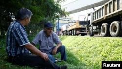 Truck drivers rest in the shade in front of the Bogdanka coal mine while they wait for coal to be loaded, in Bogdanka, Poland, Aug. 26, 2022. 