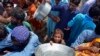 Displaced families line up to receive food as they take refuge on a roadside after fleeing their flood-hit homes in Sohbat Pur city, a district of Pakistan's southwestern Baluchistan province, Aug. 30, 2022.