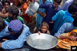 Keluarga pengungsi berbaris untuk menerima makanan setelah mengungsi dari rumah mereka yang dilanda banjir di Kota Sohbat Pur, sebuah distrik di Provinsi Baluchistan barat daya Pakistan, 30 Agustus 2022. (Foto: AP)