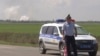 En esta imagen tomada de un video proporcionado por la televisión rusa RU-RTR el 16 de agosto de 2022, un policía bloquea el camino al lugar de la explosión en un depósito de municiones del ejército ruso cerca del pueblo de Mayskoye, Crimea.