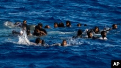 People swim next to their overturned wooden boat during a rescue operation by Spanish NGO Open Arms during at south of the Italian Lampedusa island at the Mediterranean sea, Aug. 11, 2022. 