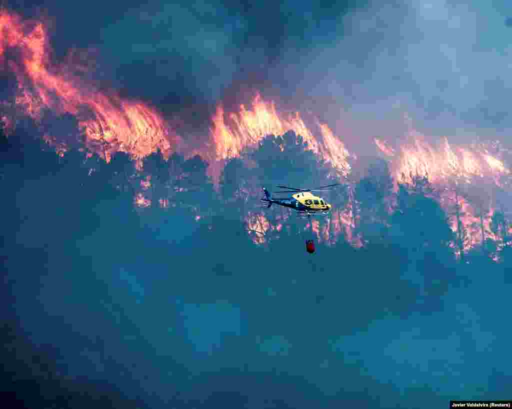 A helicopter extinguishes a wildfire burning in Albacete, Castilla-La Mancha, Spain, Aug. 30, 2022, in this picture obtained from social media.