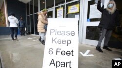 FILE - A sign asks those getting vaccinated to keep 6 feet apart during the vaccination event, at Nevada Union High School in Grass Valley, California, Jan. 27, 2021. 