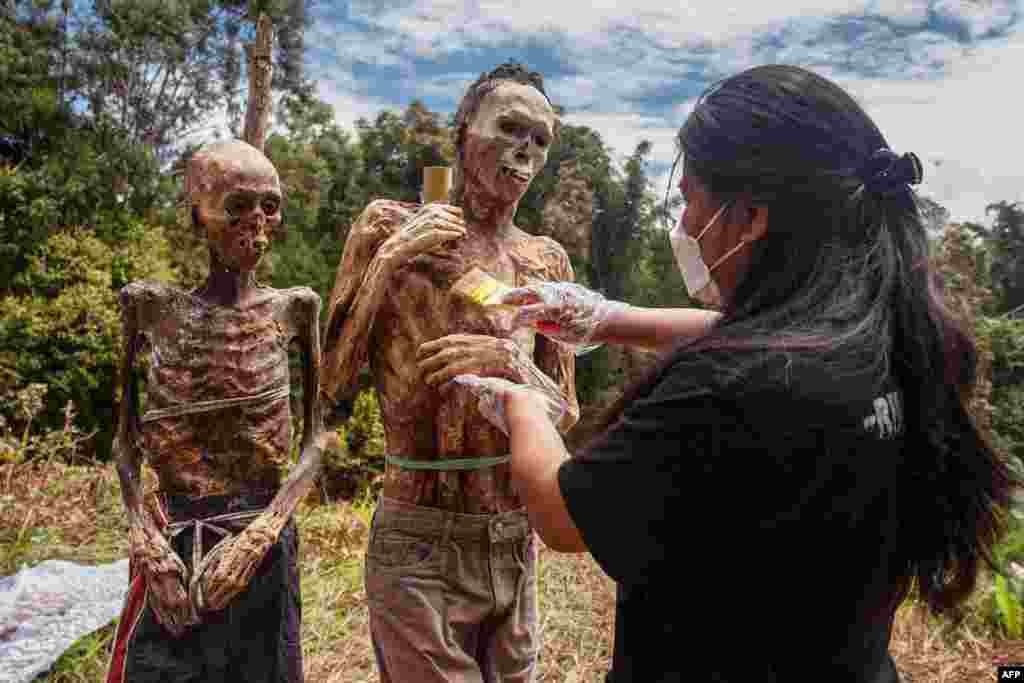 A family member of the Toraja ethnic group prepares the bodies of exhumed relatives from a community burial site to be cleaned and dressed in a series of traditional ceremonies honoring the dead known as Manene at Torea village, in North Toraja, Indonesia.