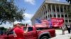 Sebuah kendaraan, yang membawa bendera bertuliskan dukungan terhadap Donald Trump untuk maju pada pemilu 2024, terlihat melaju di jalanan di luar gedung pengadilan federal Rogers di West Palm Beach, Florida, pada 18 Agustus 2022. (Foto: AP/Lynne Sladky) 