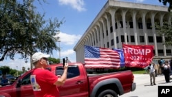 Sebuah kendaraan, yang membawa bendera bertuliskan dukungan terhadap Donald Trump untuk maju pada pemilu 2024, terlihat melaju di jalanan di luar gedung pengadilan federal Rogers di West Palm Beach, Florida, pada 18 Agustus 2022. (Foto: AP/Lynne Sladky) 