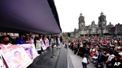 Familiares de 43 estudiantes universitarios desaparecidos muestran pancartas con los nombres y fotos de sus seres queridos desaparecidos, el séptimo aniversario de la desaparición del estudiante, en la plaza principal de la Ciudad de México, el domingo 26 de septiembre de 2021.