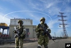 Russian soldiers guard the entrance to the Kakhovka Power Plant on the Dnieper River in southern Ukraine's Kherson region on May 20, 2022.