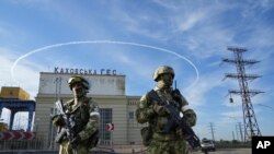 Des soldats russes gardent l'entrée de la centrale électrique de Kakhovka sur le Dniepr, dans la région de Kherson, dans le sud de l'Ukraine, le 20 mai 2022.