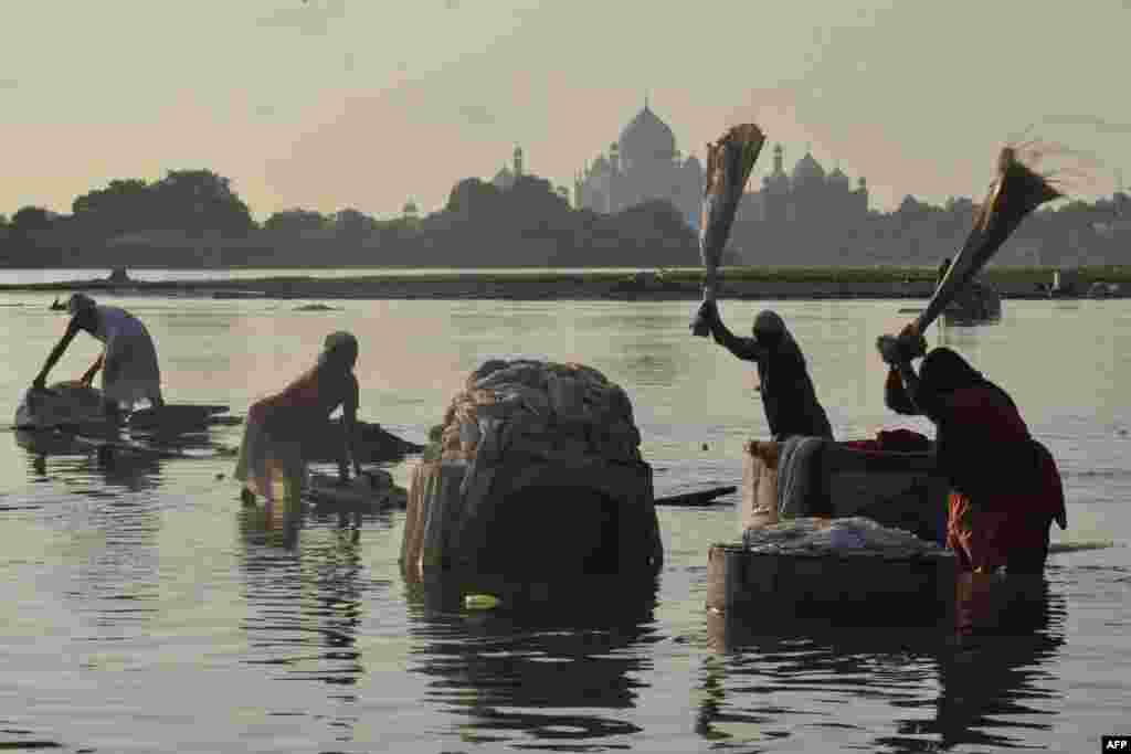 People wash clothes at Hathi Ghat along the Yamuna River with the Taj Mahal seen in the background in Agra, India.