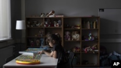 Una niña ucraniana refugiada juega un juego de mesa en un albergue para refugiados, el miércoles 17 de agosto de 2022, en Varsovia, Polonia. (AP Foto/Michal Dyjuk)