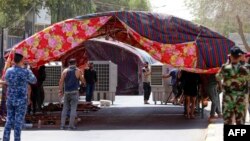 Members of the security forces pose for photos as supporters of Iraq's pro-Iran Coordination Framework set up tents on a bridge leading to the Green Zone in the capital Baghdad, on August 13, 2022.