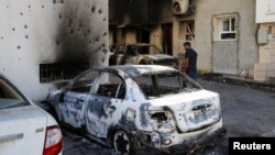FILE: A man looks at a car burned during clashes in Tripoli, Libya, Aug. 28, 2022.
