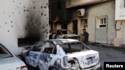 A man looks at a car burned during yesterday's clashes in Tripoli, Libya, Aug. 28, 2022.
